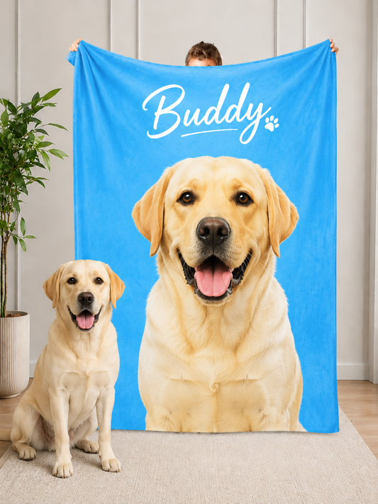 A happy yellow Labrador sits next to a person holding a sky-blue custom blanket featuring a photorealistic image of a Labrador dog and the text 'Buddy'. Perfect custom Labrador blanket for pet lovers as a travel companion or keepsake.