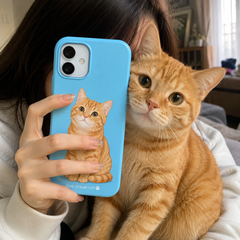Woman holding a personalized blue iPhone 17 phone case with a custom orange cat design next to a real ginger cat in a cozy home setting